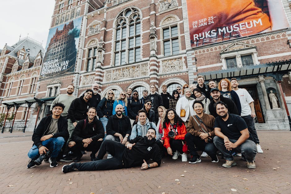 A large group poses in front of the iconic Rijksmuseum in Amsterdam, capturing a memorable moment for tourism and culture.